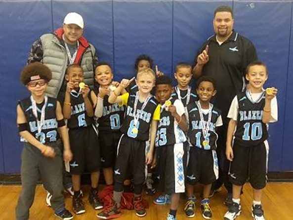 Coach Justin Wayne poses with his third grade team to celebrate winning first place in a 2014 tournament.